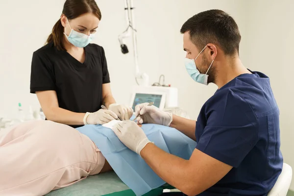 Doctor and nurse during dermatological surgery in aesthetic medical clinic