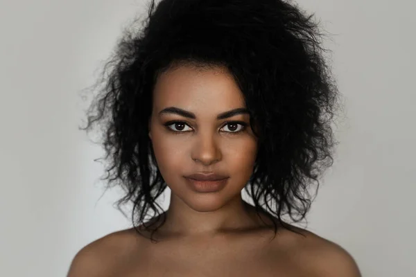 Portrait of young beautiful black woman with smooth skin on gray background