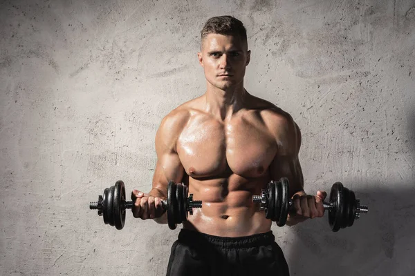 Homem Fisiculturista Jovem Muscular Trabalhando Com Halteres Contra Parede Concreto — Fotografia de Stock