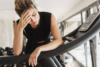 Spor salonunda spor yaptıktan sonra yorgun düşmüş atletik bir kadın.