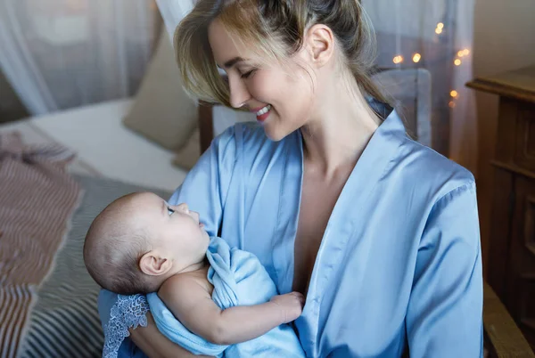 年轻美丽的母亲用蓝色布包着可爱的小宝宝的画像 — 图库照片