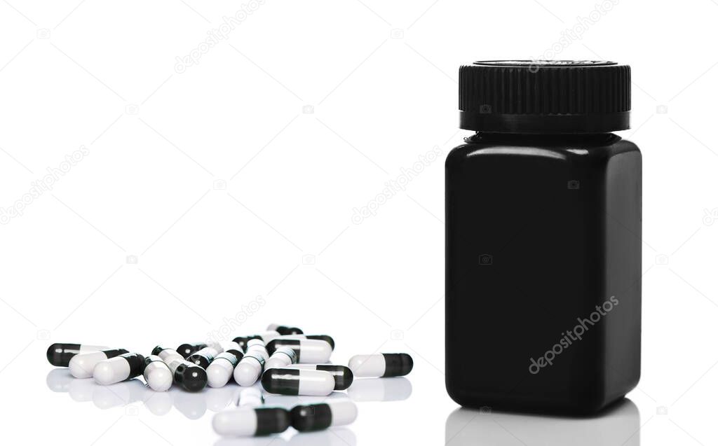 Dietary or sport supplements. Black plastic jar and capsules on white background.