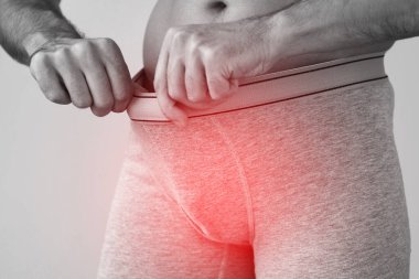 Penis ağrısı çeken külot giyen genç bir adam.