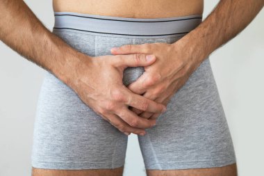 Penis ağrısı çeken külot giyen genç bir adam.