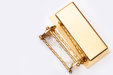 Kum saati ve beyaz arka planda altın külçeler. Değerli malzemelere yatırım kavramı.