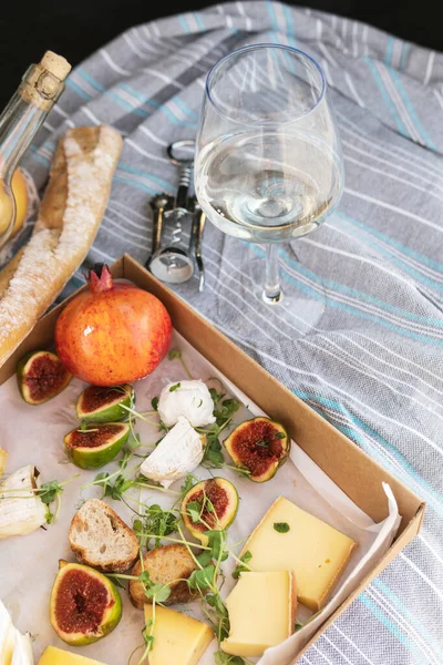 Piknikte lezzetli yemekler. Sıradan incir, peynir, ekmek ve bir bardak şarap.