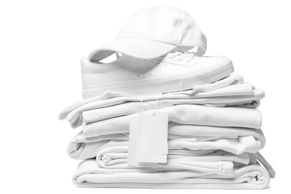 一堆堆新的白色衣服 训练员和棒球帽 其空白的服装标签与白色背景隔离 — 图库照片