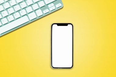 Ofis tarzı beyaz arka planda telefon bilgisayarının üstündeki üst görünüm