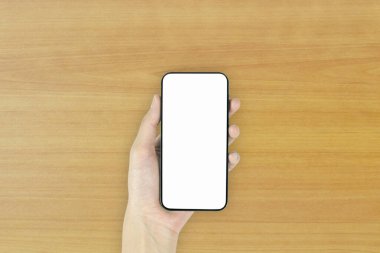 Ofis tarzı beyaz ahşap zeminde telefon bilgisayarının üstündeki en üst görünüm..