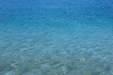 Mavi şeffaf deniz suyu dokusu. Sakin, temiz bir okyanus suyu arka planı. Yaz tatili kavramı.