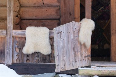 Tanned sheepskins rugs hang on a fence at a wood house in countryside. Travel, tourism and environment concept. clipart