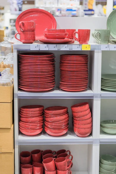 Tabaklar mağazada satılır. Bir süpermarketteki raflar için farklı kırmızı bardaklar, kaseler ve tabaklar..