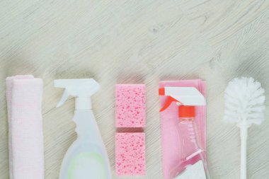 Detergents in spray. Cleaning accessories. Top view of pink cleaning supplies on wooden background. 