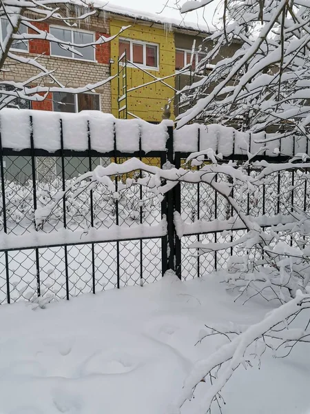 冬の街の雪のフェンスと明るい家の眺め — ストック写真