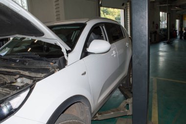 Beyaz araba oto tamirhanesinde gri bir asansöre monte edildi.