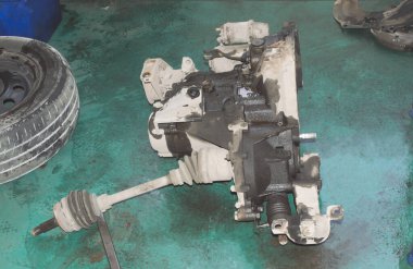 Yarı dingilli bir otomobil manuel vites bir oto tamirhanesinde yeşil katta yatıyor.