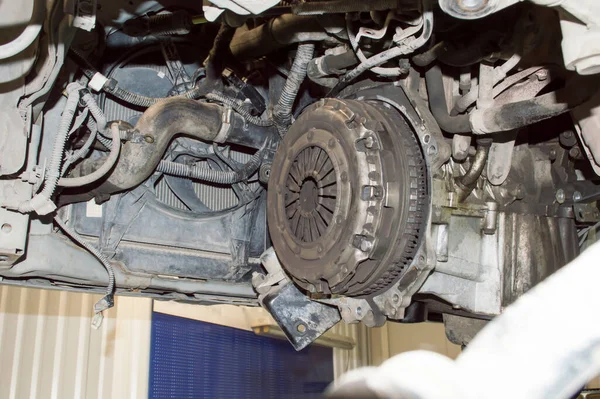 Bottom view of the engine compartment of the car, which is located in an auto repair shop with the manual transmission removed, the clutch is visible