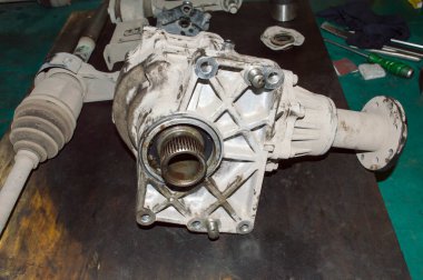 Nakil çantası ve dört tekerden çekişli bir arabanın yarım aksları bir oto tamirhanesinde yerde yatıyor.