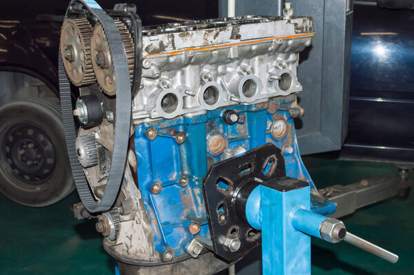 The blue internal combustion engine unit installed on the engine repair stand in the auto repair shop