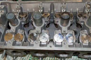 Otomobil tamir atölyesinin masaüstündeki motor bloğunun başına yerleştirilen valf musluklarının görüntüsü