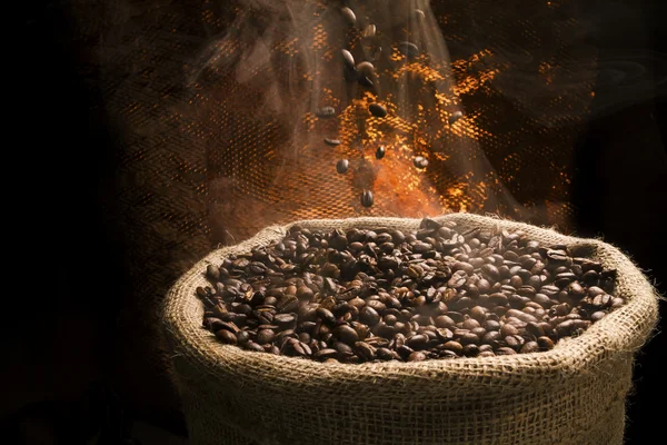 Sack full of still hot, freshly roasted coffee beans with the falling coffee beans. — Stock Photo, Image