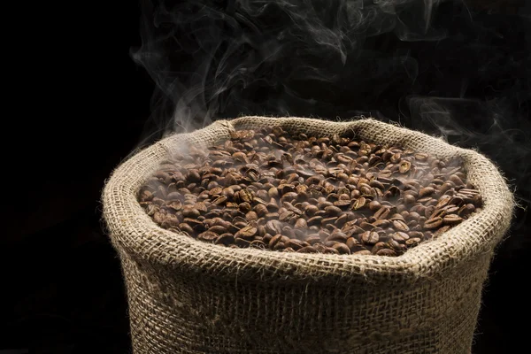 Sack full of still hot, freshly roasted coffee beans with the smoke rising in the air. — Stock Photo, Image