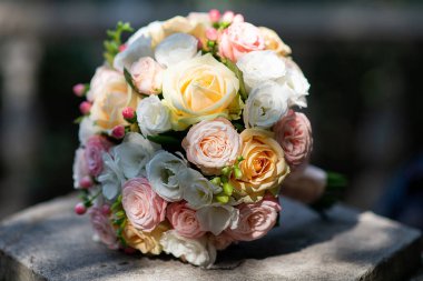 a wedding bouquet of pink and white roses lies on a concrete slab in nature. wedding decor and floristr