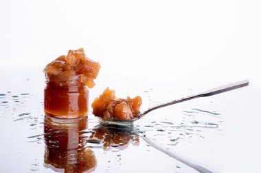 Kavanozda reçel ve kaşık. Elma ve armut reçeli beyaz ayna arka planında su damlaları olan bir kaşıkta. sağlıklı doğal tatlı kavramları