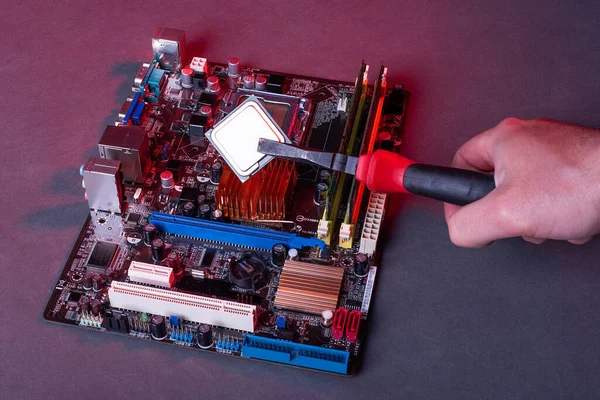 high performance personal computer repair, hands with pliers inserting processor into motherboard socket, red neon ligh