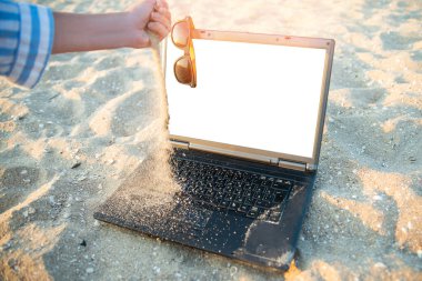 Kumsalda kumda dizüstü bilgisayar işi. Gözlükler güneşe karşı. Dinlenme ve rahatlama.