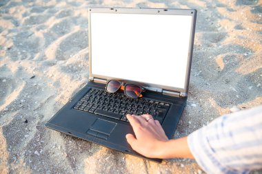 Kumsalda kumsalda dizüstü bilgisayar. Gözlükler güneşe karşı. Dinlenme ve rahatlama.