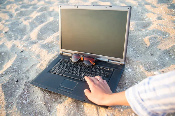 laptop on the beach in the sand. glasses against the sun. rest and relaxation by the se