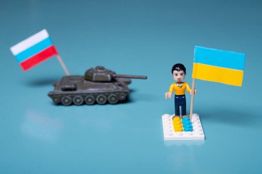 Ukrayna bayrağı dumanlı lego adam ve mavi arka planda bir tank. Vatansever ülke savaşı kavramı Rusya ve Ukrayna