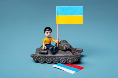 Ukrayna bayrağı dumanlı lego adam ve mavi arka planda bir tank. Vatansever ülke savaşı kavramı Rusya ve Ukrayna