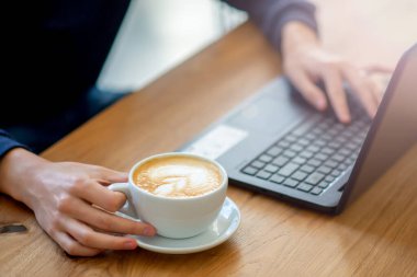 hand prints coffee in a laptop cup in a cafe. 