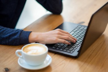 hand prints coffee in a laptop cup in a cafe. 
