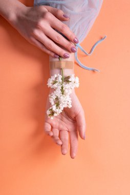 Turuncu arka planda leylak çiçekleri olan sıhhiyeli bir kızın elleri. kadın sağlığı konsepti cilt temizliği