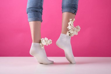 Pembe arka planda bir demet leylak çiçeği yerleştirilmiş çoraplı bir kızın bacakları. Kadın damarları ve bacakları kavramı