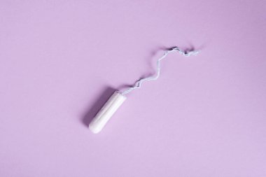 Dişi bir tampon, pastel bir leylak arka planda yatar. Boşluk düzlemini kopyala Kadın sağlığı ve regl.
