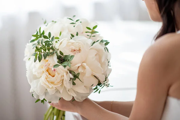 wedding bouquet of white peonies in the hands of the bride close-up. Pastel soft colors. concept for event agencies and floristr