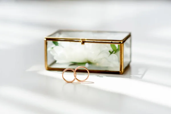 wedding gold rings on the background of a glass box on a background of white fabric. concept for event agencies for the ceremony of the bride and groo