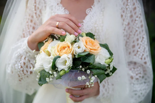 the bride in a white dress with sleeves holds a bouquet of bloom flowers in her hands. idea for event agencies wedding salon