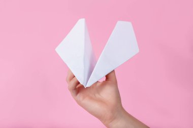 El ve kağıt uçak pembe arka planda. Çocuk oyun oynuyor. Çocuk umudu kavramı. Oyuncak bebek. seyahat beyaz uçak