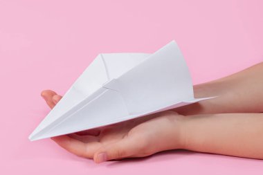 Pembe arka planda çocukların elinde kağıt uçak. Bebekle seyahat oyunları. Geleceğe uçma kavramı. Akıllı telefonsuz oyunlar. Origami kağıtları. Okulda oyunlar