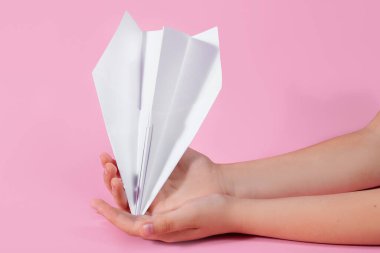 Pembe arka planda çocukların elinde kağıt uçak. Bebekle seyahat oyunları. Geleceğe uçma kavramı. Akıllı telefonsuz oyunlar. Origami kağıtları. Okulda oyunlar