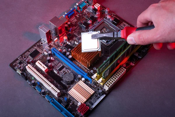 high performance personal computer repair, hands with pliers inserting processor into motherboard socket, red neon ligh