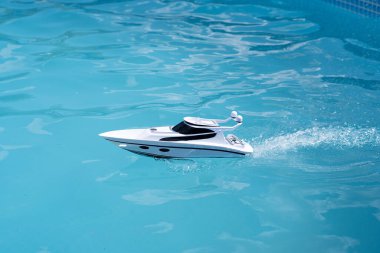 children's toy white boat in the blue pool. water games in summer in sunny weathe