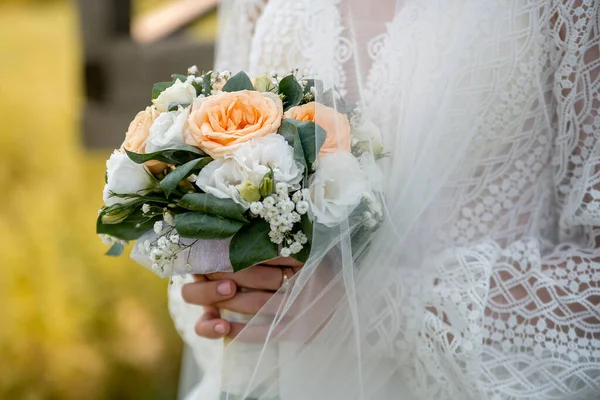 the bride in a white dress with sleeves holds a bouquet of bloom flowers in her hands. idea for event agencies wedding salon