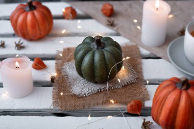 autumn decor of pumpkins and candles in october. cup of tea and garlands. idea for hallowee