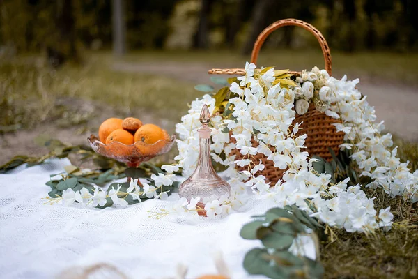 autumn decor. basket on a picnic mat with fruit apples and oranges with flowers. rest at natur